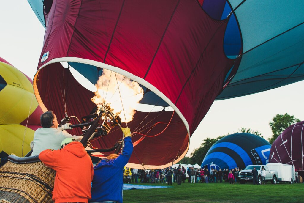 three men inflating a hot air balloon. This image is used as a money inflation metaphor for Alpha Wealth Financial Advisors