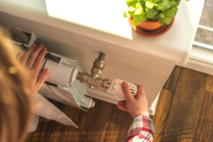 A woman turning her heating down on her radiator to help save money and lower costs